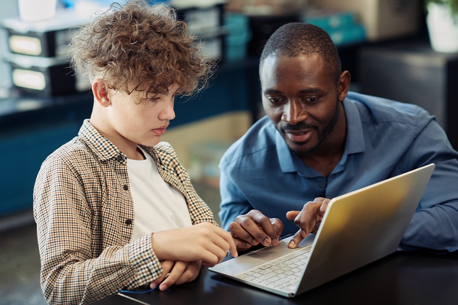Student and teacher working together on a laptop.
